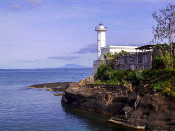 Lighthouse by sea against sky