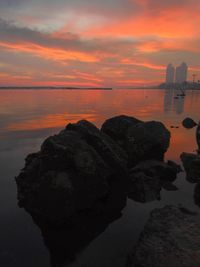 Rock formation on sea against sky during sunset