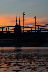 Silhouette of bridge over river during sunset