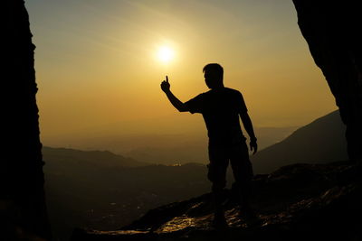 Silhouette man standing on mountain against sky during sunset