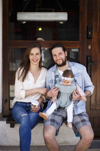 Full length of happy friends sitting outdoors