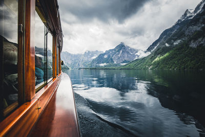 Boat moving in lake against cloudy sky