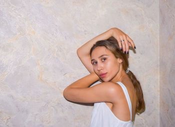 Portrait of beautiful woman standing against wall