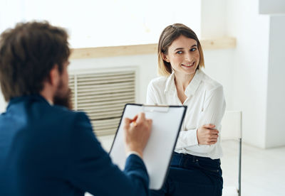 Young woman using digital tablet while standing in office