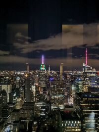 Illuminated buildings in city against sky at night