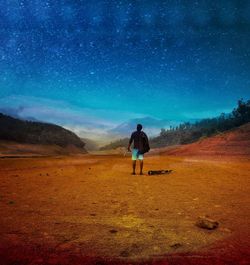 Rear view of man standing on field against sky