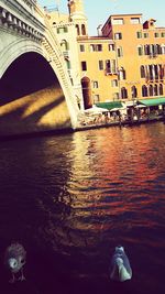 Rear view of arch bridge over river in city