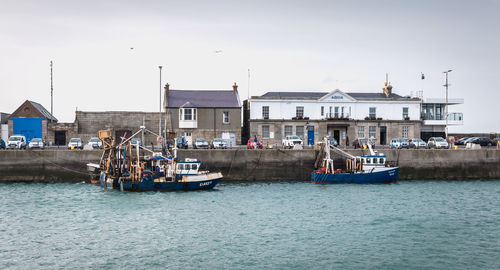 Boats moored in sea against buildings in city