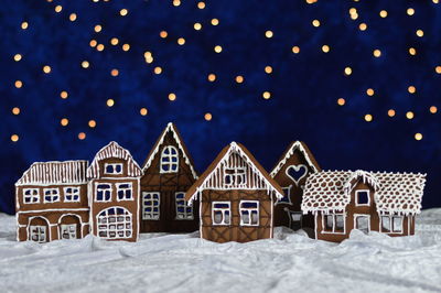Houses in snow against clear sky at night during winter