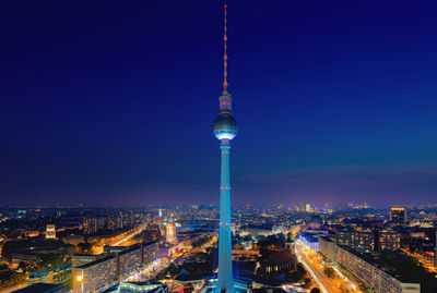 Illuminated cityscape against clear blue sky at night