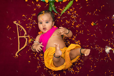 Cute indian boy dresses as lord rama with bow and flowers from top angle