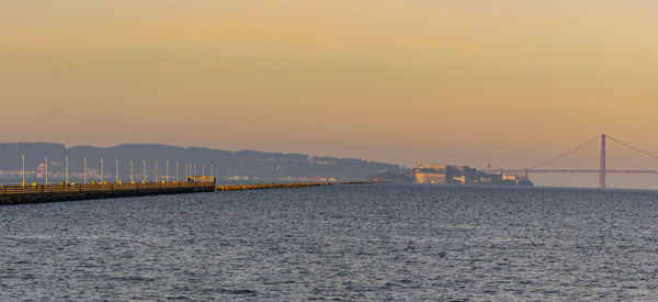 Bridge over sea against sky during sunset