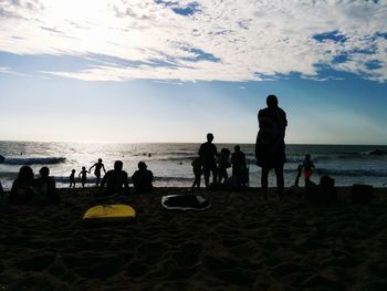 People playing at beach against sky