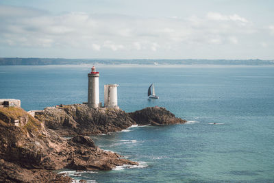 Lighthouse by sea against sky