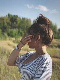 Side view of young woman standing on grassy field at park