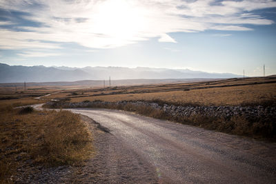 Road amidst agricultural field against sky