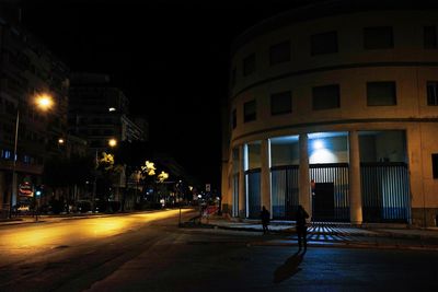 Illuminated street amidst buildings in city at night