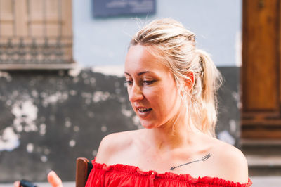 Close-up of young woman sitting against wall