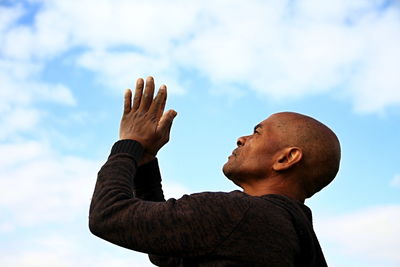 Low angle view of man gesturing against sky