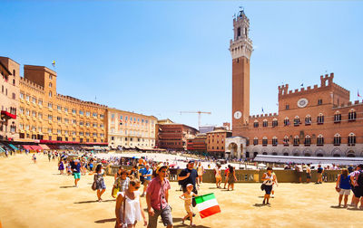 Group of people in front of buildings against clear sky