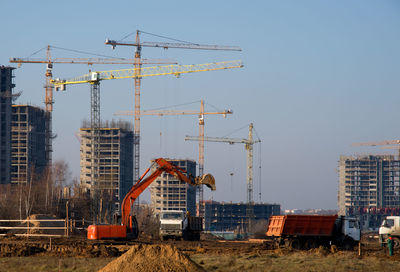 Cranes at construction site against sky in city