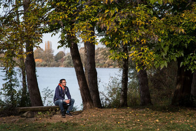 Man sitting on bench against trees at park