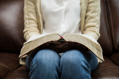 Midsection of woman reading book at table