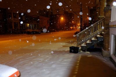 Snow in illuminated city at night during winter