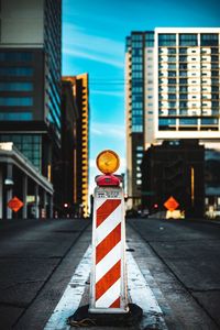 Road sign on street in city against sky