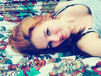 Close-up portrait of smiling young woman lying on bed