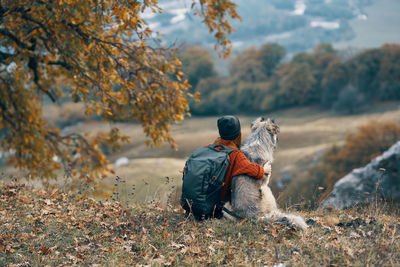 Rear view of young man with dog in background