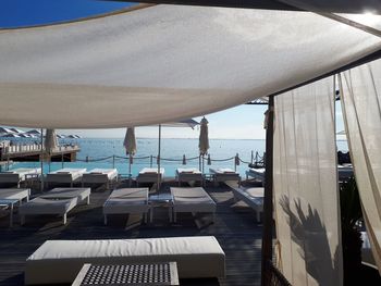 Chairs and tables at beach against sky