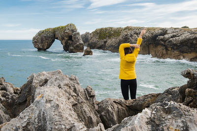 Rear view of man standing on rock by sea