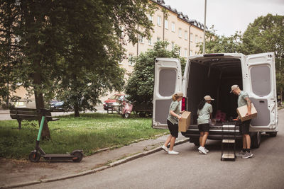 Male and female coworkers loading boxes in delivery van