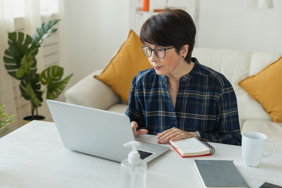 Side view of young woman using digital tablet while sitting at home