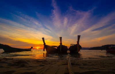 Silhouette boats on beach against sky during sunset