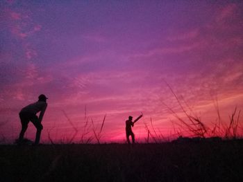 Silhouette people playing on field against sky during sunset