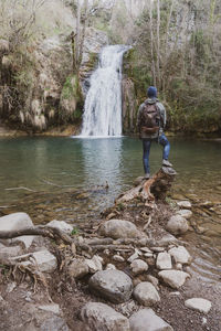 Man standing by waterfall in forest