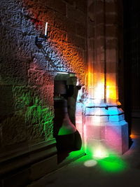 Colorful lights reflecting on bell by wall in historic building