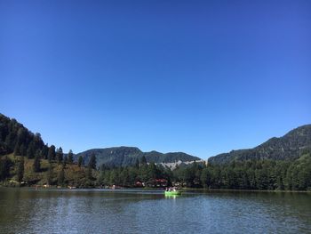 Scenic view of lake and mountains against clear blue sky