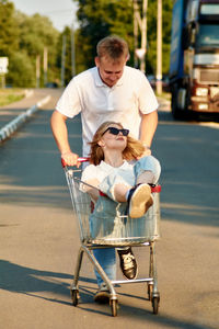 A beautiful young couple is having fun, a guy is pushing a shopping cart,