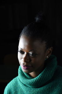 Close-up portrait of smiling young woman against black background