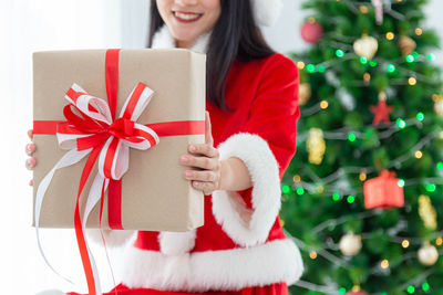 Midsection of woman holding red christmas tree in box