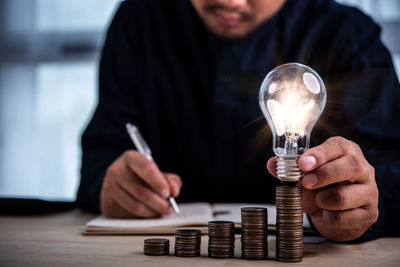 Midsection of man holding light bulb on table