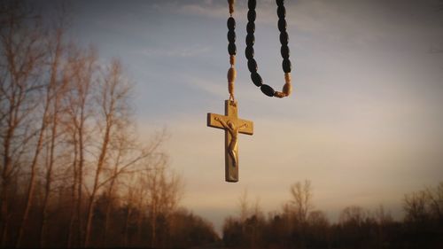 Cross pendant hanging against sky