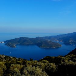 High angle view of sea and mountains against clear blue sky