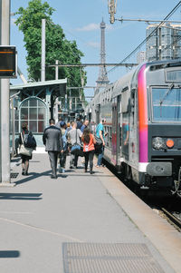 People at station with eiffel tower against sky