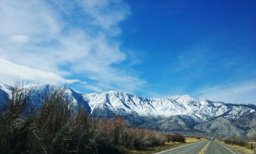 Road passing through mountains against cloudy sky