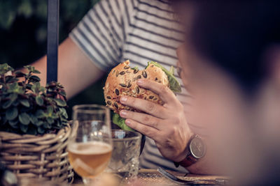 Midsection of man having burger in restaurant