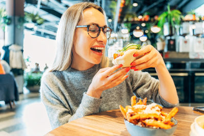 Portrait of young woman eating food in restaurant